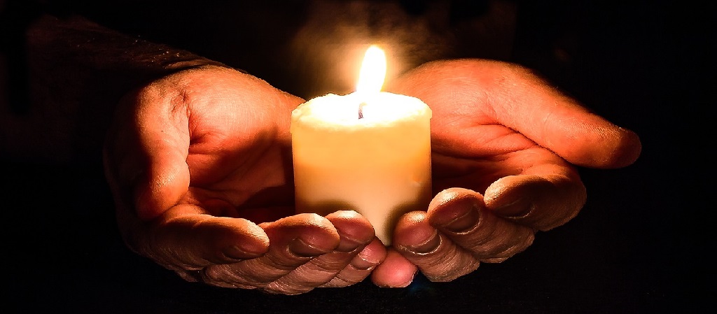 Lighted candle on hands